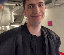 a man wearing a black jacket and a black shirt smiles