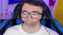 a man wearing glasses and headphones is making a funny face while sitting in a chair .