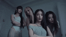 a group of women standing next to each other with their arms crossed and a man standing behind them