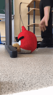an angry bird stuffed animal is laying on the floor in a classroom