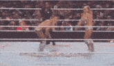 two women wrestling in a ring with a crowd watching