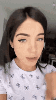 a woman in a white shirt with butterflies on it