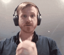 a man wearing headphones and a blue shirt is making a funny face