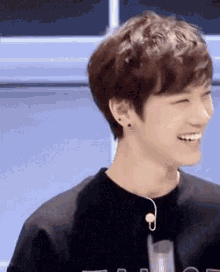 a young man wearing a black shirt and earphones is smiling and laughing .