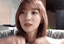 a close up of a woman 's face with a ponytail and bangs looking at the camera .
