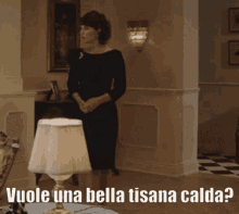 a woman in a black dress is standing next to a lamp with the words vuole una bella tisana calda written below her
