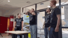 a group of people are standing around a table and one of them is drinking from a cup
