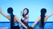 three women are dancing in front of a blue background with the word gifs on the bottom right corner