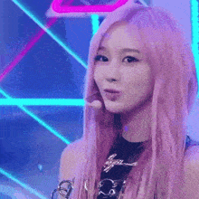 a woman with pink hair is standing on a stage with a microphone in her hand .
