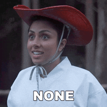 a woman wearing a red cowboy hat with the word none on the bottom