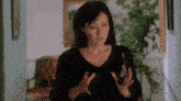 a woman in a black shirt is standing in a hallway with her hands up .