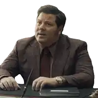a man in a suit and tie sits at a desk with a pen in his hand