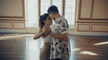 a man in a floral shirt is dancing with a woman in a white top