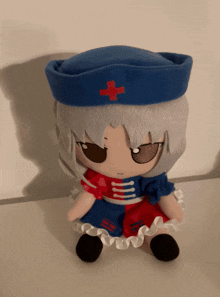 a stuffed doll with a red cross on her hat is sitting on a table