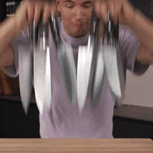 a man is holding a bunch of knives in his hands