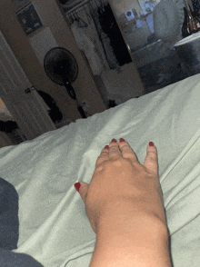 a woman 's hand with red nail polish is on a bed