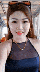 a woman wearing sunglasses and a necklace is taking a selfie with her phone .