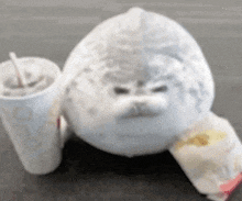 a stuffed seal is sitting next to a cup of soda and a bag of french fries