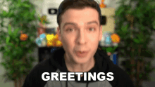a man wearing a hat is saying greetings in front of a plant