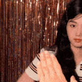 a woman with long black hair is standing in front of a curtain with tinsel