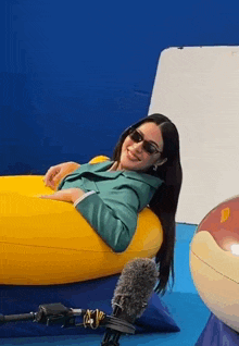 a woman wearing sunglasses is laying on a yellow raft .