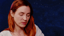 a woman with red hair and a white shirt is looking down