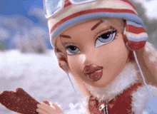 a bratz doll wearing a striped hat and gloves is holding a ice cream bar