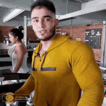 a man in a yellow shirt is standing in a gym with a woman behind him