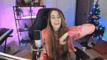 a woman sitting in front of a microphone in front of a twitch sign