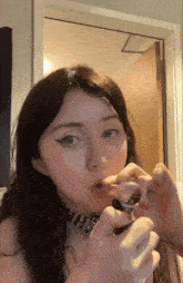a girl with a choker on her neck is smoking a cigarette