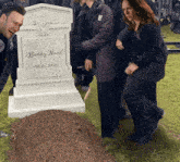 a group of people are standing around a grave of bobby nash