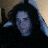 a man with curly hair is sitting in a chair with headphones on his head .