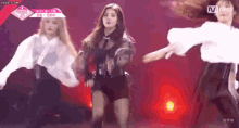 a group of girls are dancing on a stage with a sign that says mnet on it .