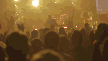 a crowd of people watching a band perform on stage with their hands in the air