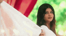 a woman in a white dress is holding a white cloth and looking at the camera .
