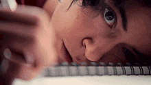 a close up of a woman 's face laying on a spiral bound notebook