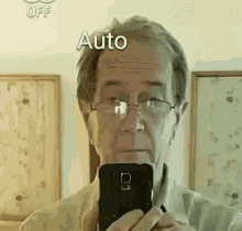 a man with glasses is taking a picture of himself in a mirror with the words auto above him