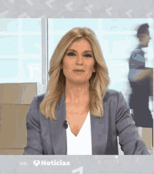 a woman is on a tv show called noticias and is wearing a blue jacket