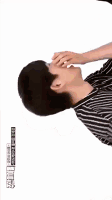a man in a striped shirt covering his mouth with his hands
