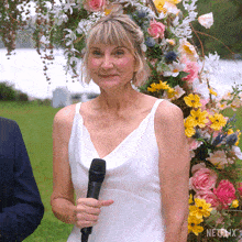 a woman in a white wedding dress is holding a microphone and smiling