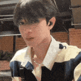 a young man wearing a striped shirt and a necklace .