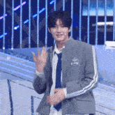 a young man in a suit and tie is waving at the camera