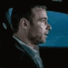 a man in a suit is smoking a cigarette while sitting in the back seat of a car .