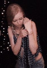 a woman is singing into a microphone while wearing headphones and a striped shirt