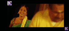 a man and a woman are standing next to each other and smiling . the woman is wearing a green sari .