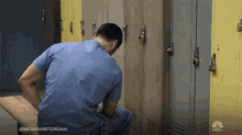 a man in scrubs sits on a bench in front of lockers with the hashtag #newamsterdam on the bottom