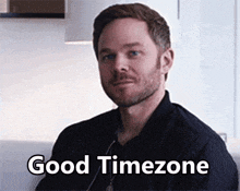 a man with a beard is smiling and says good timezone .