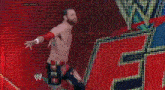 a wrestler is dancing in front of a large screen with a w logo on it