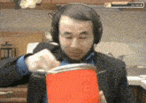 a man wearing headphones is holding a red container in his hand