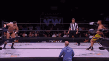 a man in a blue hoodie is watching a wrestling match in a ring that says aew on it